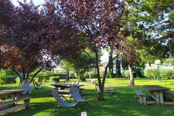 Photo du parc du bonheur, incitant à la détente. Les transats et les tables et bancs à l'ombre nous invitent à nous y installer avec un livre ou un rafraichissement